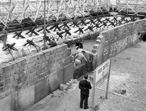 1962年，来自东德的砌墙工人修筑柏林墙，一旁负责守卫的是东德的士兵
